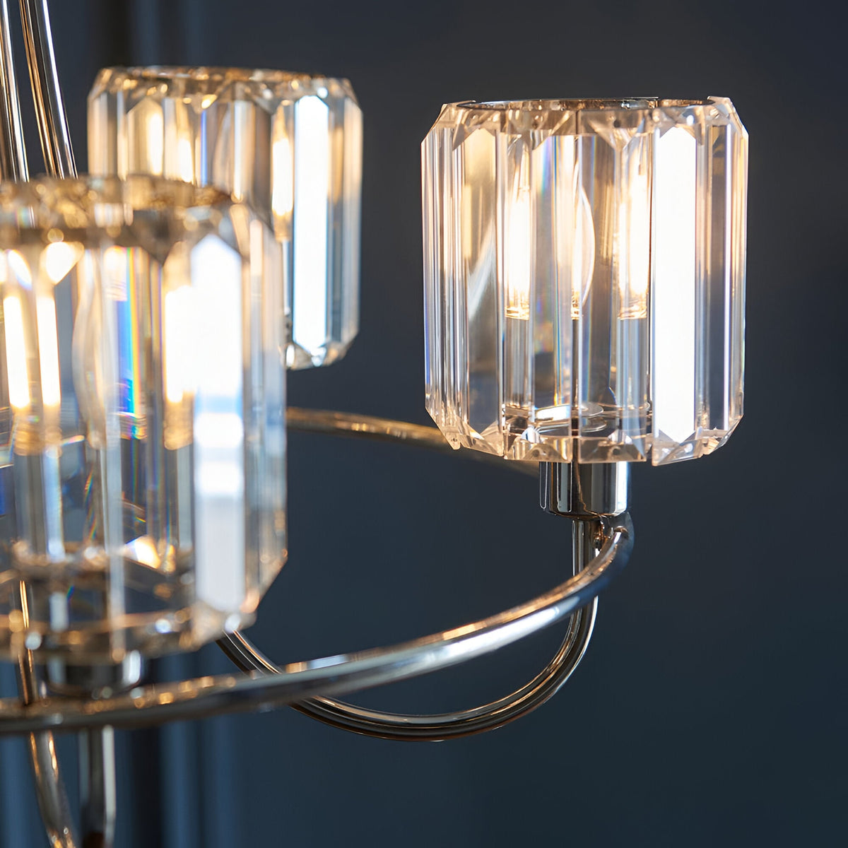 Close-up of the Clementine 5 Light Pendant in nickel, showing faceted crystal glass shades on curved metal arms against a dark background.
