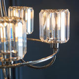 Close-up of the Clementine 5 Light Pendant in nickel, showing faceted crystal glass shades on curved metal arms against a dark background.
