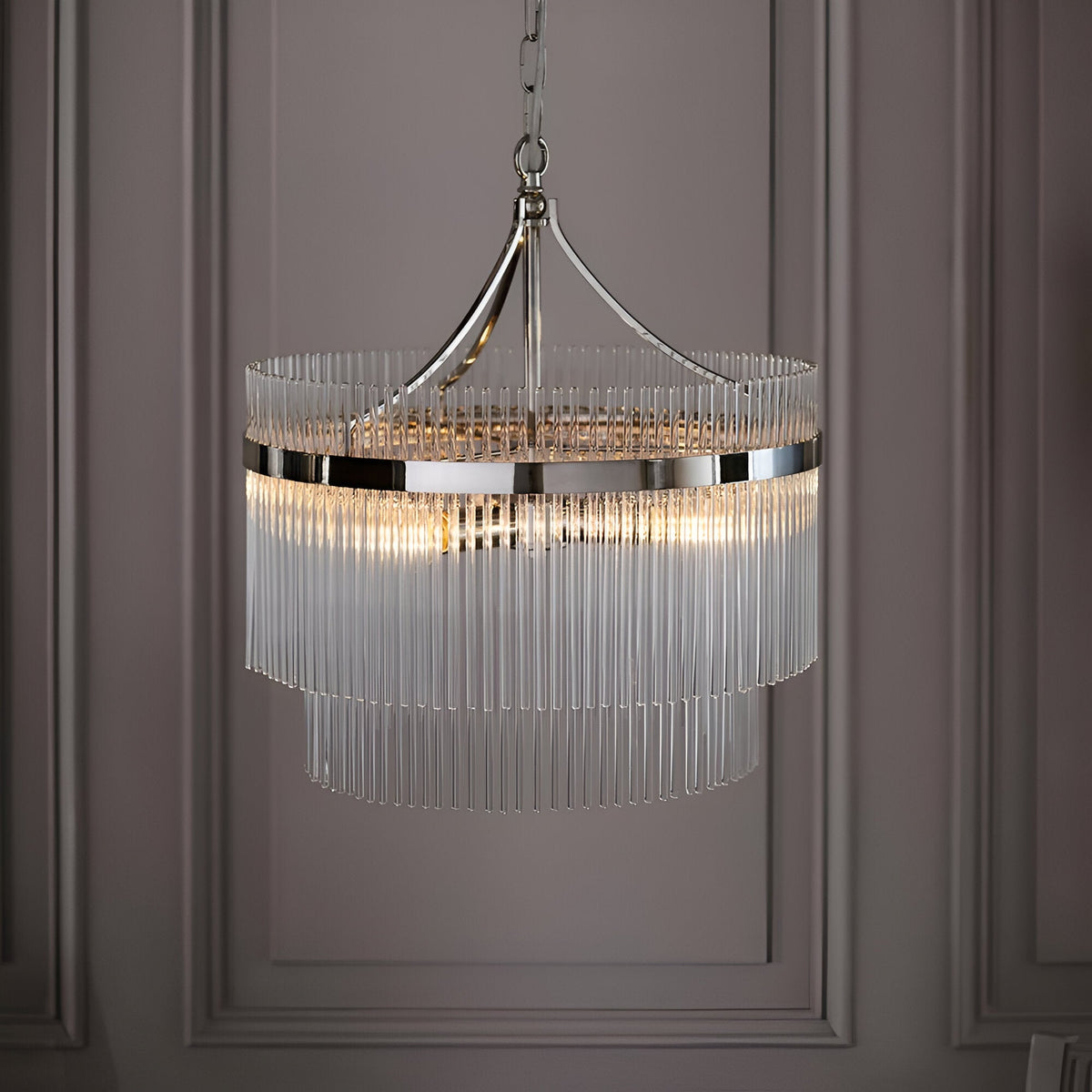 Beaumont 5 Light Pendant in nickel, a two-tier fixture with clear glass rods and chain suspension, shown illuminated against a panelled grey wall.
