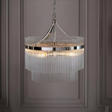 Beaumont 5 Light Pendant in nickel, a two-tier fixture with clear glass rods and chain suspension, shown illuminated against a panelled grey wall.
