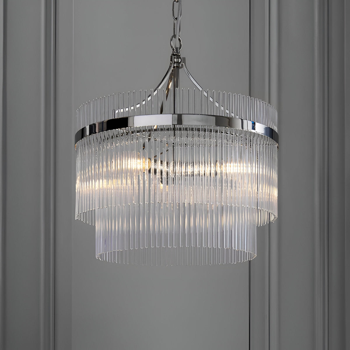 Beaumont 3 Light Pendant in nickel with tiered clear glass rods and chain suspension, hanging against a grey panelled wall.