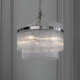 Beaumont 3 Light Pendant in nickel with tiered clear glass rods and chain suspension, hanging against a grey panelled wall.