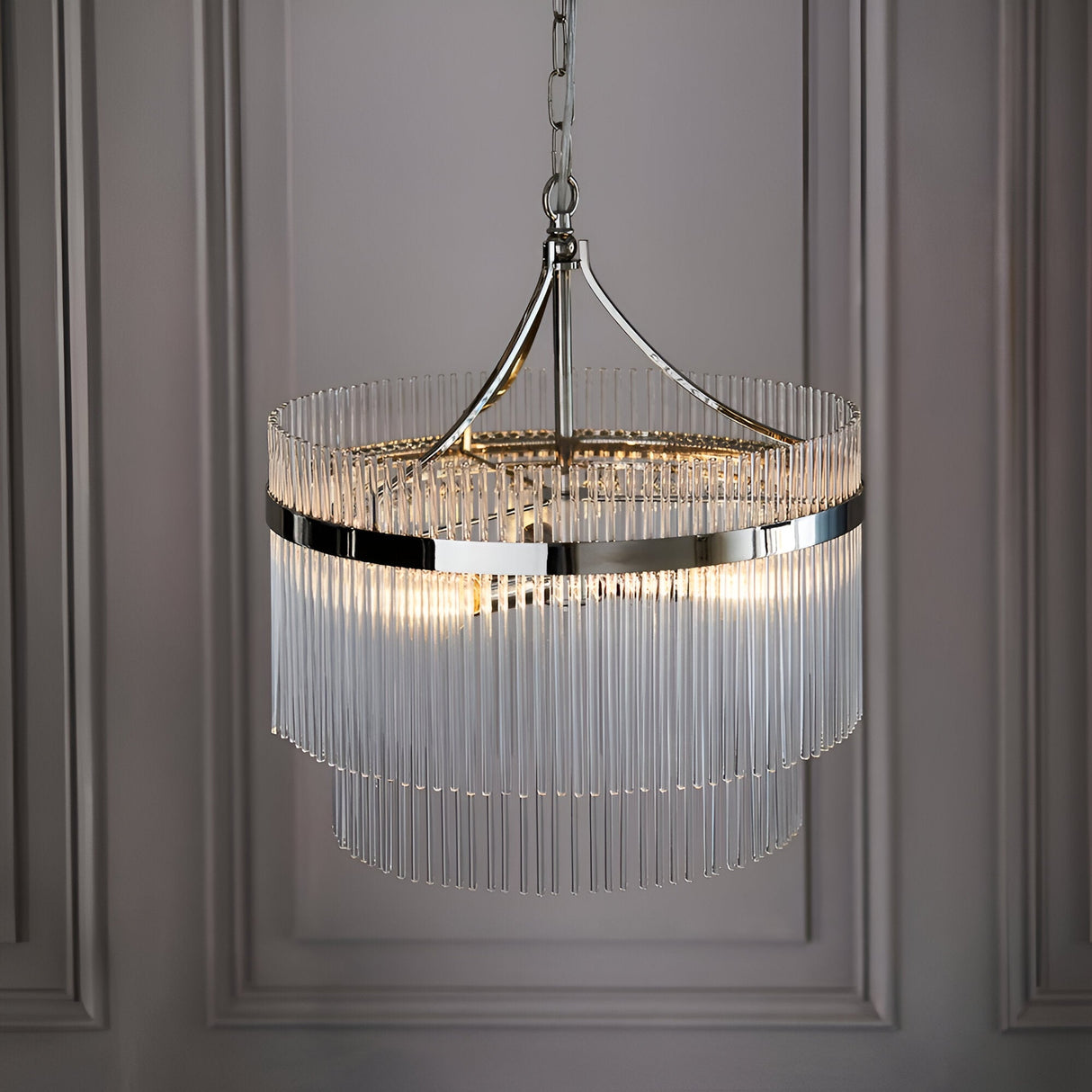 Beaumont 3 Light Pendant in nickel, a two-tier round fixture with clear glass rods and chain suspension, hanging against a panelled grey wall.