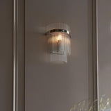 Endon Beaumont wall light in nickel with curved clear glass rods and lit E14 bulb, mounted on a panelled neutral wall.