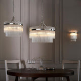 Endon Beaumont wall light in nickel with clear glass rods, shown lit beside two tiered glass-rod pendant lights above a dining table in a grey panelled room.