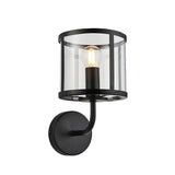 Endon Ellery wall light in matt black with a clear cylindrical glass shade, curved arm, round backplate and single E14 filament bulb.