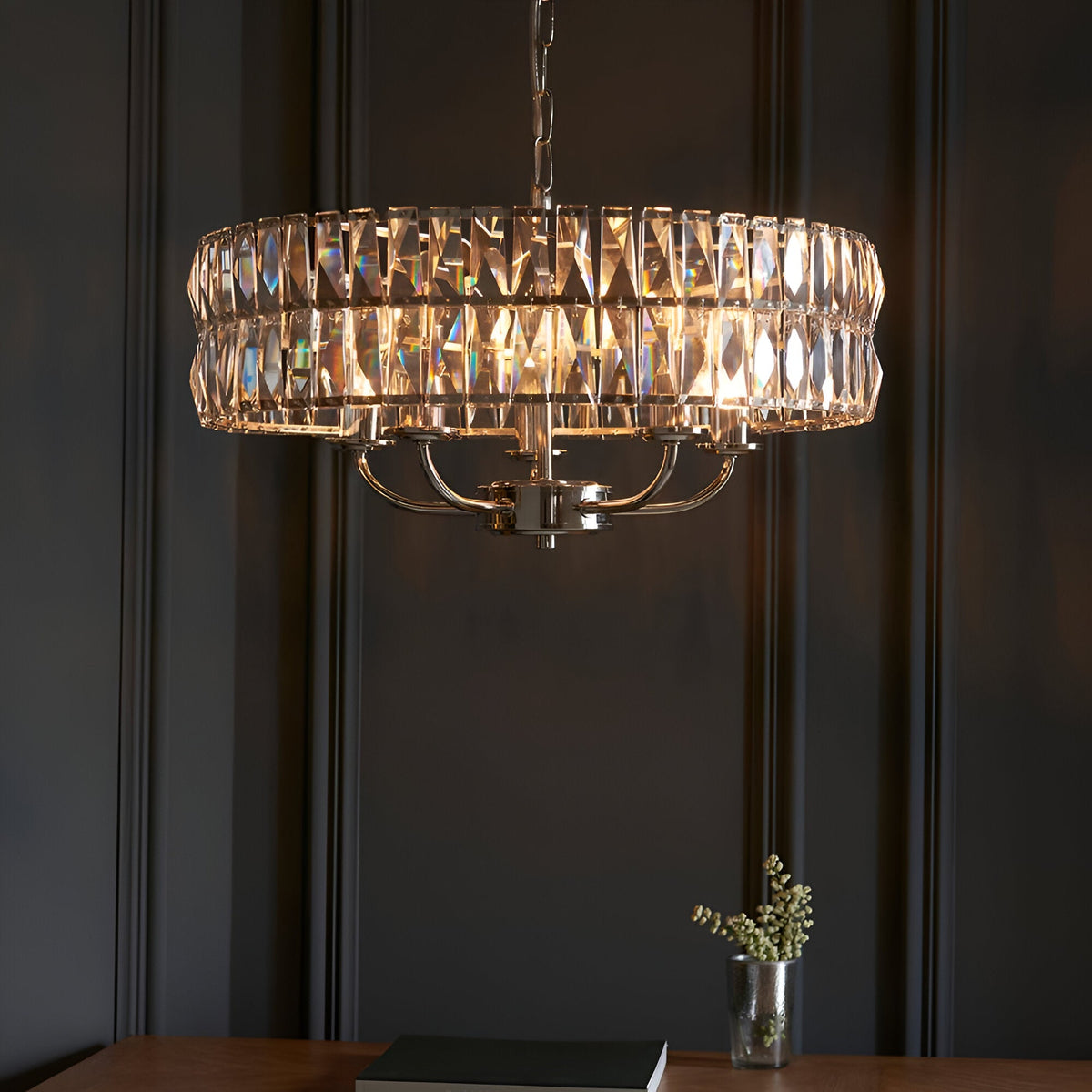 Endon Bevmont 5 light pendant in nickel with faceted crystal glass drum shade on a chain, casting light patterns against a dark panelled wall.