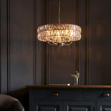 Endon Bevmont 5 light pendant in nickel with tiered clear cut faceted glass shades, illuminated above a dark panelled sideboard in a dim living room.