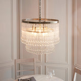 Endon Bramgrove 5 light tiered pendant with clear glass droplets and antique brass frame, suspended by chain above a dining table in a panelled room.