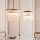 Endon Bramgrove pendant lights with tiered clear glass droplets on antique brass frames, shown in two sizes above a dining table setting.