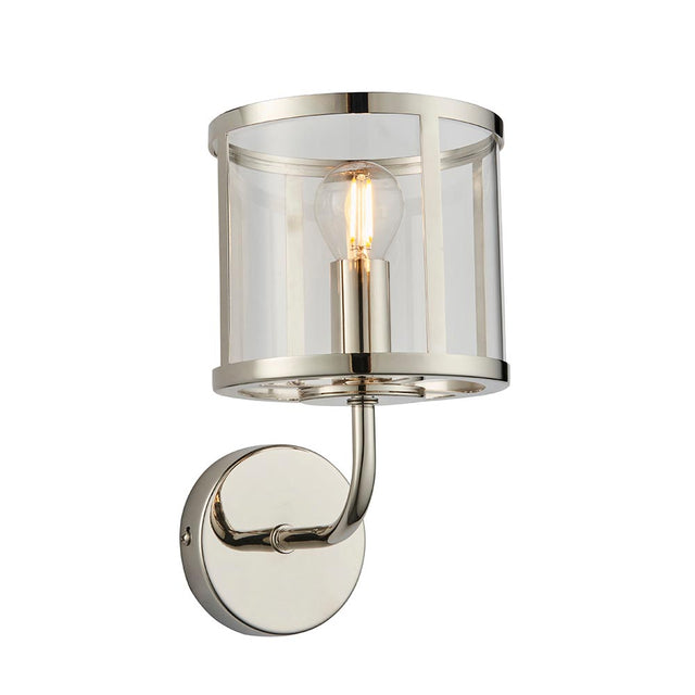 Ellery Wall Light in nickel with a cylindrical clear glass shade, single E14 bulb, curved arm and round backplate, on a plain white background.
