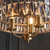 Close-up of the Endon Bevmont 3 light pendant in brass, showing curved arms, E14 candle lamps and a tiered drum shade of cut faceted glass.
