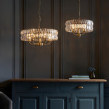 Endon Bevmont 3 light pendants in brass with tiered cut faceted glass shades, hung above a navy sideboard in a panelled room.