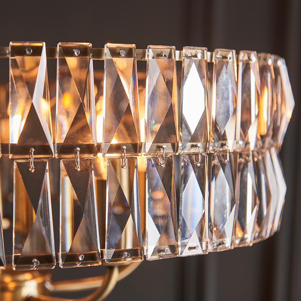 Close-up of the Bevmont 5 Light Pendant in brass, showing faceted crystal-look glass panels linked with brass frames and pins.