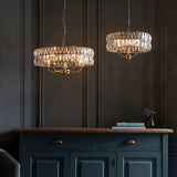 Bevmont 5 Light Pendant in brass with faceted crystal glass drum shade, shown lit above a dark blue sideboard in a panelled dining room.