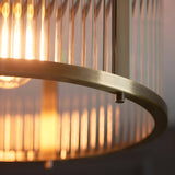 Close-up of the Rothbury flush ceiling light in antique brass, showing the brushed brass ring and ribbed glass shade with a lit E27 bulb.