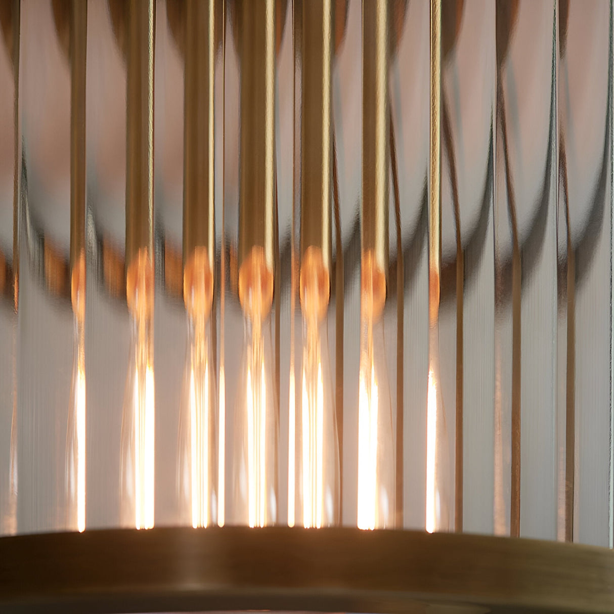 Close-up of the Rothbury flush ceiling light in antique brass, showing ribbed glass rods and warm glowing bulbs beneath the brass mount.