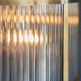 Rothbury 3 Light Pendant in antique brass, close-up of ribbed glass shades glowing warmly around a brass frame edge.