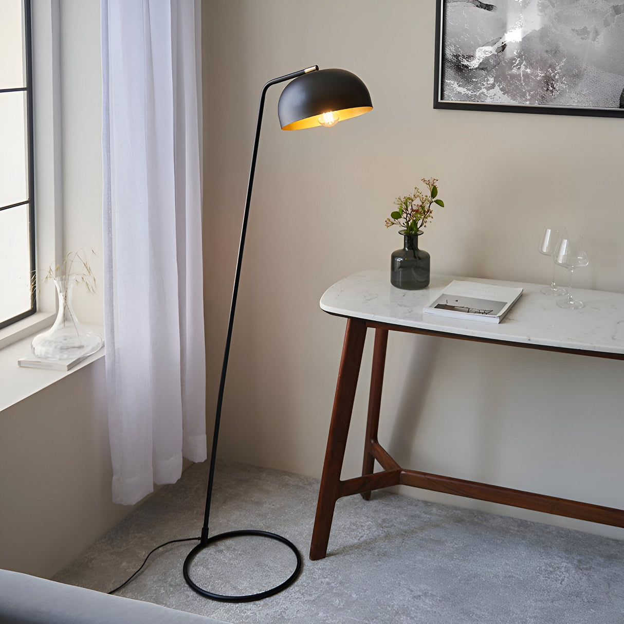 Endon Ashdon floor lamp in matt black with adjustable dome shade and brass-lined interior, beside a marble console table in a neutral living space.