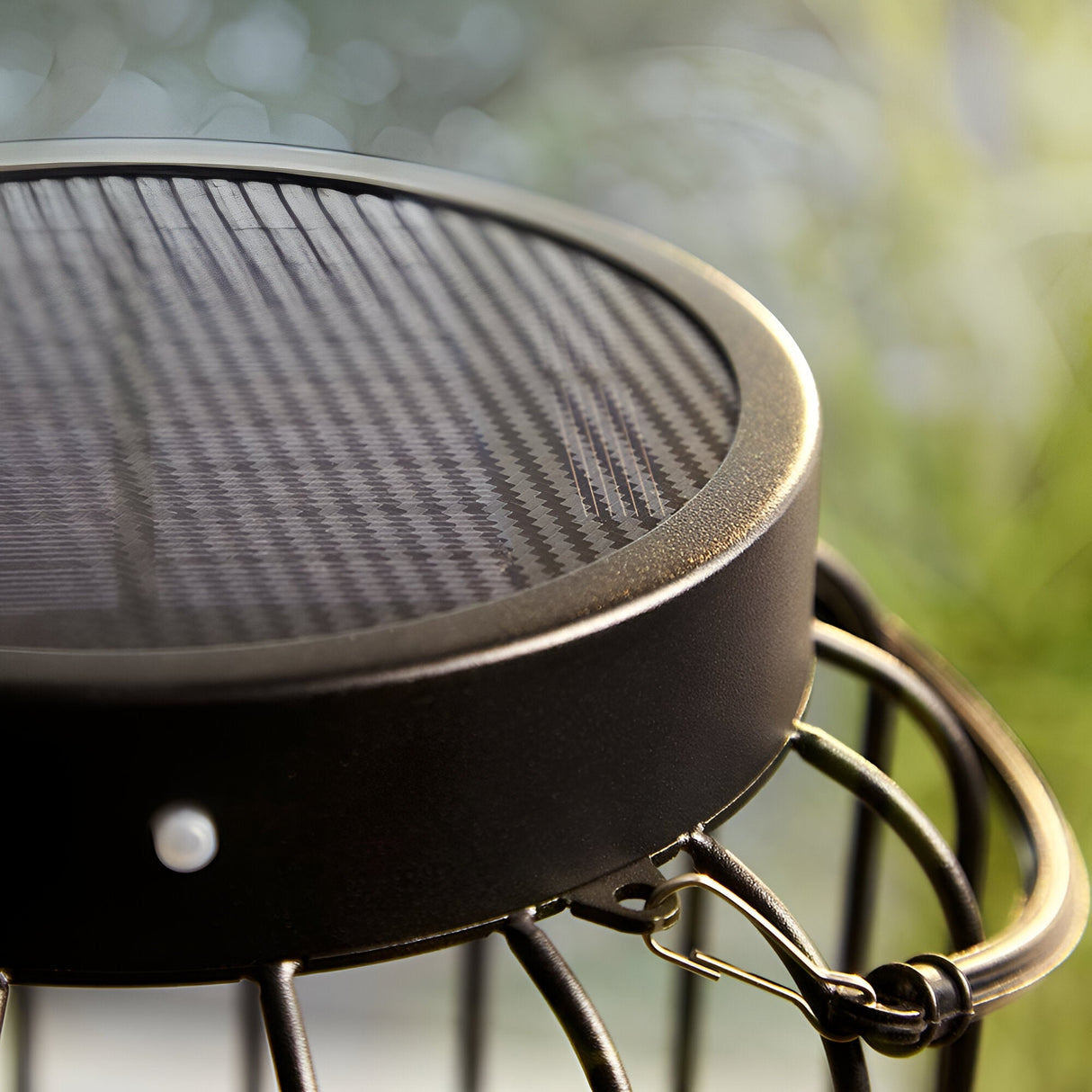 Close-up of the Endon Cranwood LED solar table lamp showing its matt black metal cage top and solar panel, set outdoors against soft greenery.