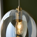 Close-up of the Brockmere Pendant's satin brass fitting and E27 bulb inside an oval champagne lustre glass shade with warm reflections.