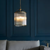 Endon Caldcombe 4 light pendant with ribbed glass shade and antique brass frame, suspended from a chain against a deep blue panelled living room wall.