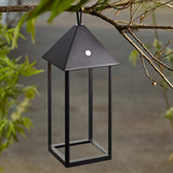 Endon Brenmont large matt black aluminium lantern table lamp with pyramid top and open frame, hanging from a tree branch outdoors.