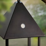 Close-up of the Endon Brenmont large table lamp in matt black, showing the pyramid aluminium top and touch control button, hung outdoors.