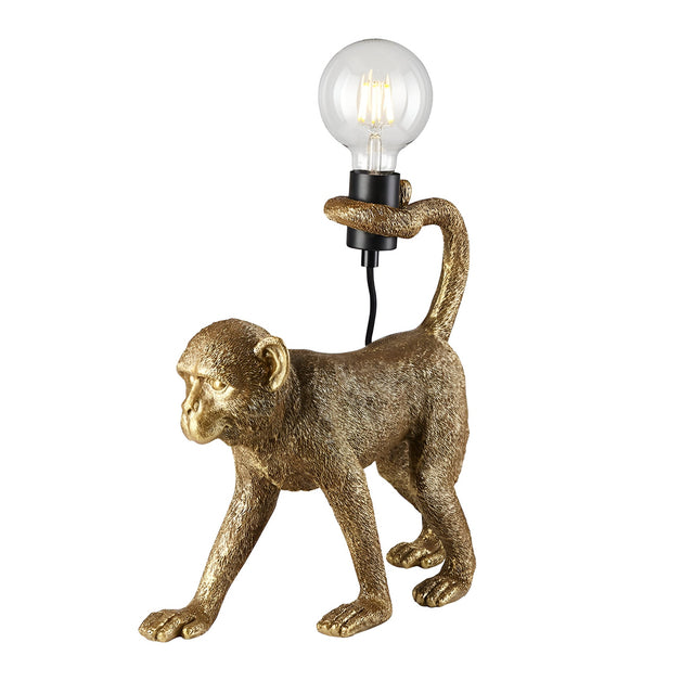 Endon Belvoir table lamp in gold resin, modelled as a walking monkey holding an exposed filament bulb in its tail, shown on a white background.