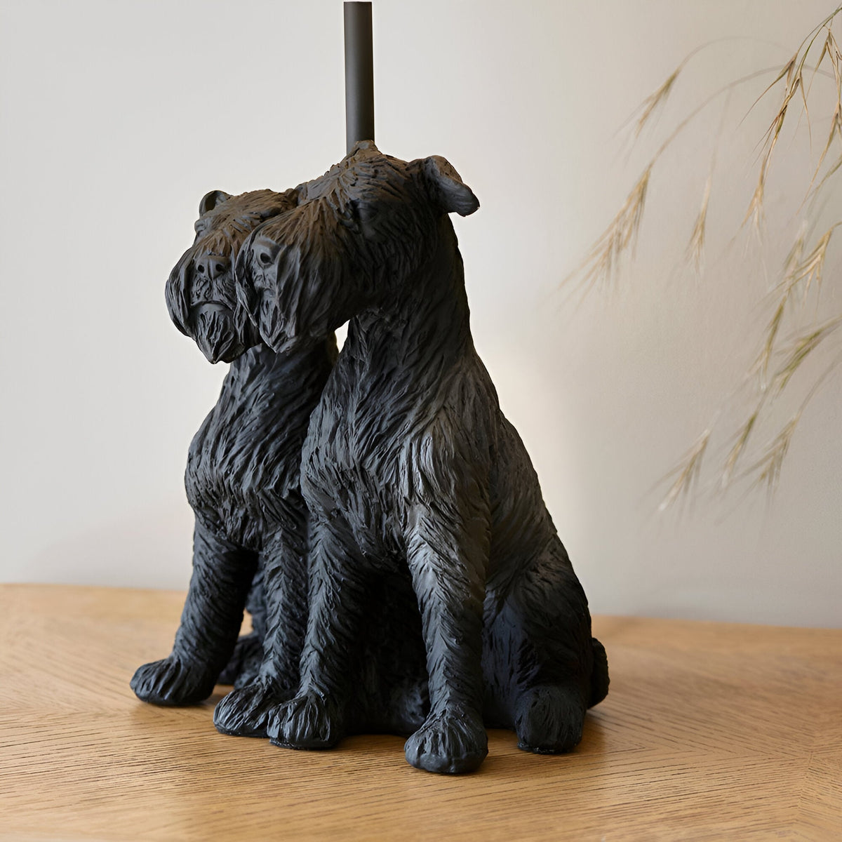 Danegrove Table Lamp in Black, resin base sculpted as two seated dogs with textured fur, matt black finish, black lamp stem, shown on a wooden surface.