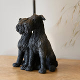 Danegrove Table Lamp in Black, resin base sculpted as two seated dogs with textured fur, matt black finish, black lamp stem, shown on a wooden surface.