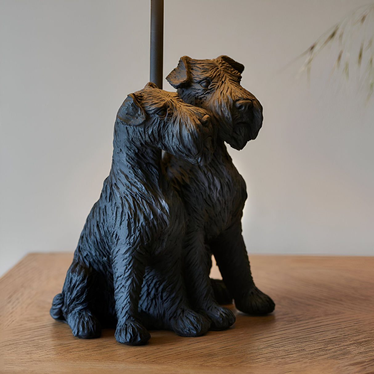 Danegrove Table Lamp base in matt black resin, shaped as two seated dogs with textured fur detail, on a wooden surface with black rod support.