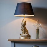 Endon Brambury table lamp with a vintage gold resin fox base and black tapered fabric shade, styled on a wooden console beside a brass vase.