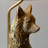 Close-up of the Endon Brambury table lamp's hand-painted resin fox head in vintage gold finish, beside the slim gold lamp stem against a light background.