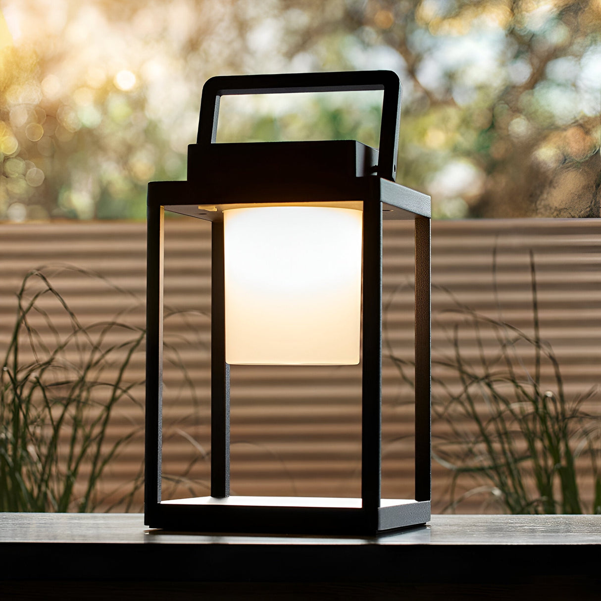 Endon Danedon portable USB rechargeable table lamp in matt black aluminium with white polycarbonate diffuser and carry handle, on an outdoor tabletop.