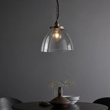 Wentworth Pendant in silver with clear glass dome shade and exposed filament bulb, hung on a black chain above a dining table.