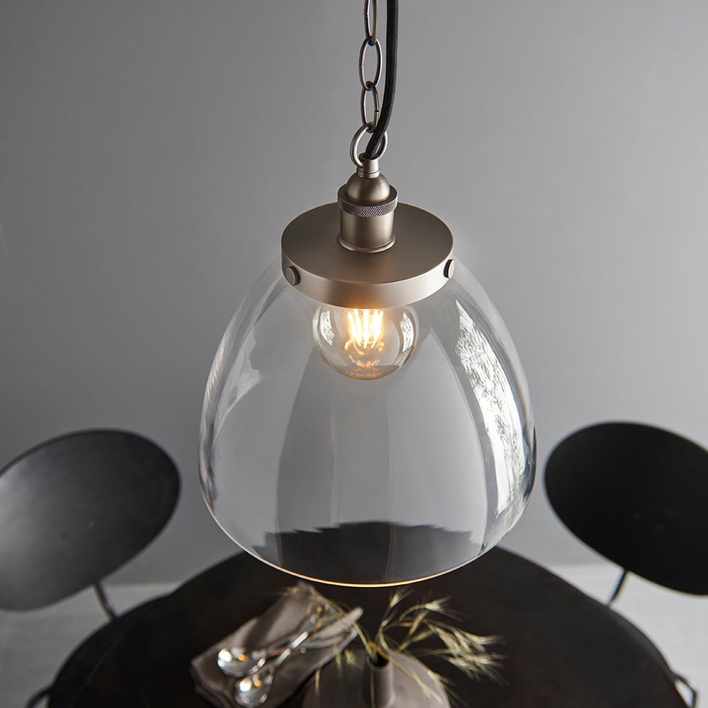 Wentworth Pendant in silver with a clear glass dome shade, knurled lampholder, and chain suspension, shown lit above a table setting.