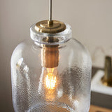 Caldwood Pendant close-up showing textured clear glass shade, antique brass fitting, and lit E27 bulb inside.