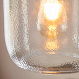 Caldwood Pendant close-up showing textured clear glass shade with antique brass fitting and glowing E27 bulb inside.