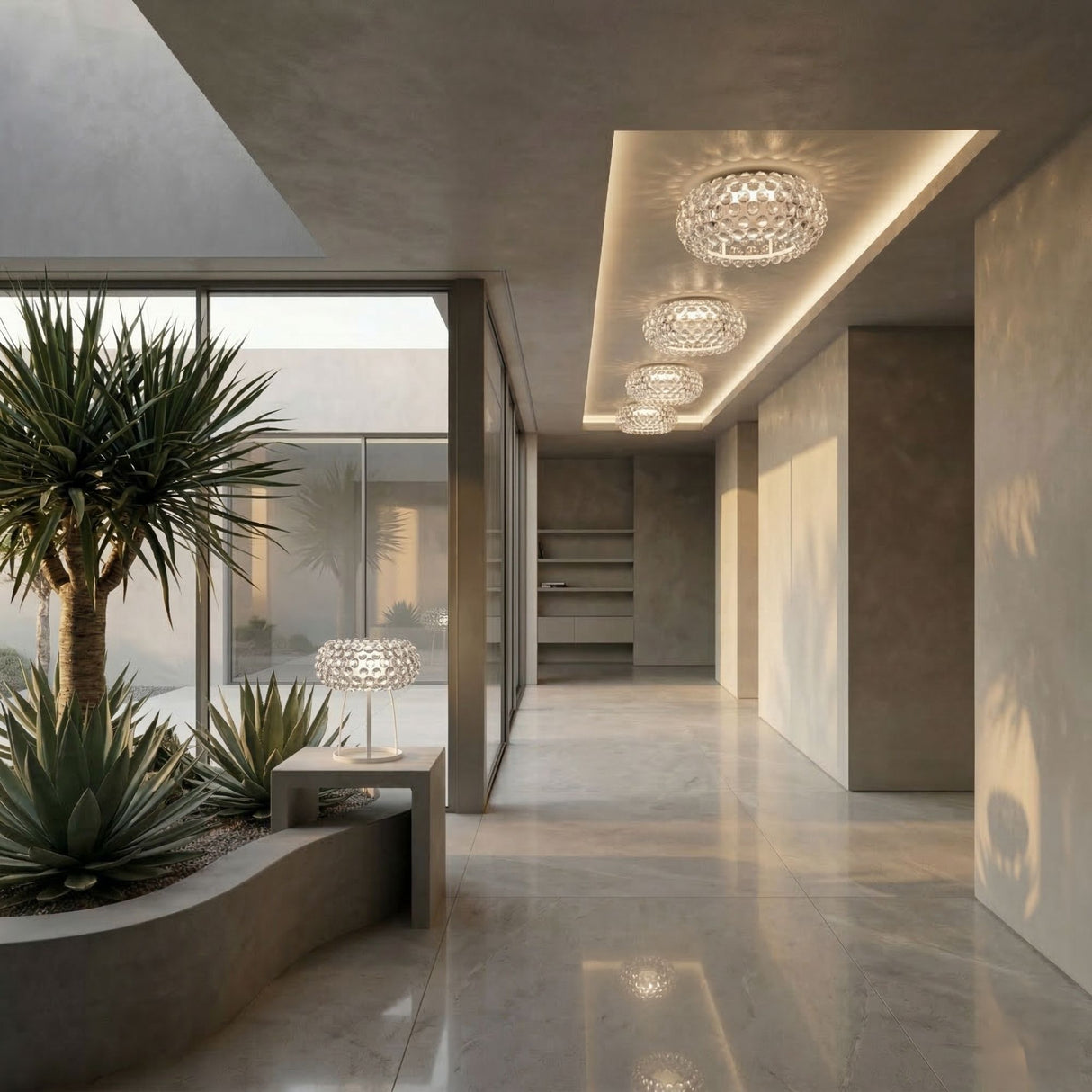 Modern, minimalist interior with large windows, marble floors, recessed lighting, and a sculptural Briller LED Flush Ceiling Light - Transparent. An indoor planter with desert plants sits by a glass wall leading to an outdoor courtyard.