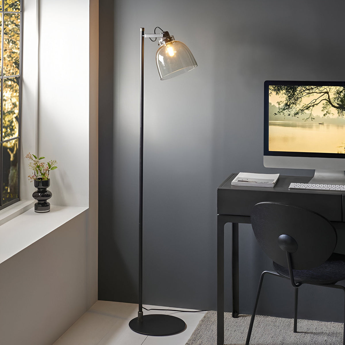 Endon Camden task floor lamp in matt black with adjustable smoked glass shade and filament bulb, beside a dark desk and computer by a window.