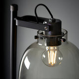 Close-up of Endon Camden Task Floor Lamp in matt black with knurled chrome details and smoked grey glass shade housing a lit E27 filament bulb.