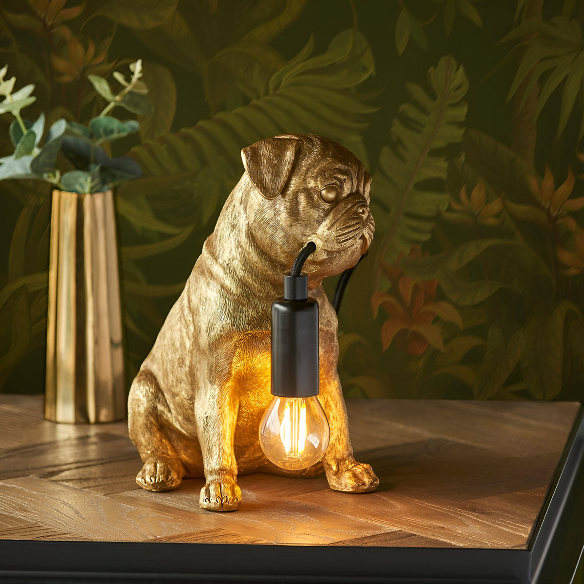 Endon Charthurst table lamp shaped as a gold resin pug figure holding a black E14 lamp holder with filament bulb, on a wooden surface.