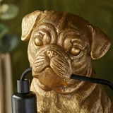 Close-up of the Endon Charthurst table lamp's gold resin pug figure, showing sculpted facial detail beside the black fabric cable and inline switch.