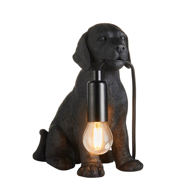 Endon Brockworth table lamp shaped as a matt black resin Labrador puppy holding an E14 filament bulb by a black cable, on a plain white background.