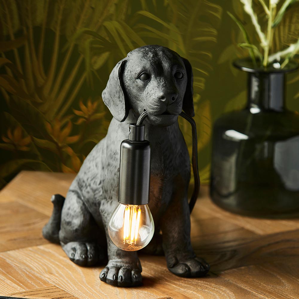 Endon Brockworth matt black resin Labrador puppy table lamp holding an E14 filament bulb, on a wooden surface beside a dark glass vase.