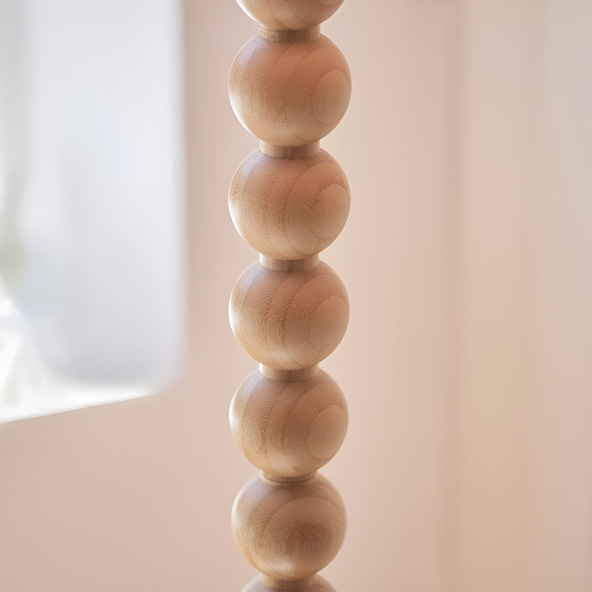 Close-up of the Endon Ashwood floor lamp base showing stacked natural bamboo wood spheres with visible grain against a soft pink background.