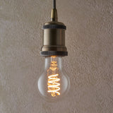Pendant light with antique brass fitting and knurled detailing, fitted with a 4W E27 LED filament GLS bulb showing a warm white spiral filament.