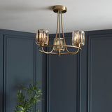 Endon Clementine 3 light semi-flush ceiling light in brass with faceted crystal glass shades, mounted on a white ceiling above dark blue panelled walls.