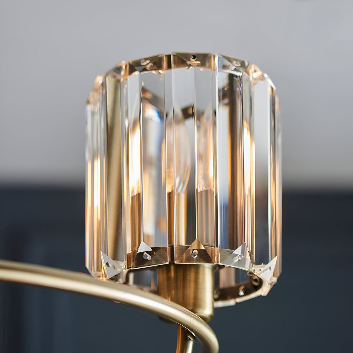 Close-up of one glass shade on the Endon Clementine 3 Light Semi-Flush Ceiling Light in brass, showing faceted crystal panels around a lit E14 lamp.